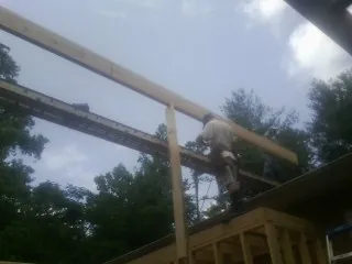 Carpenter setting a ridge beam over a new addition frame — Ice Dam Removal by Roofing Brothers in Hedgesville