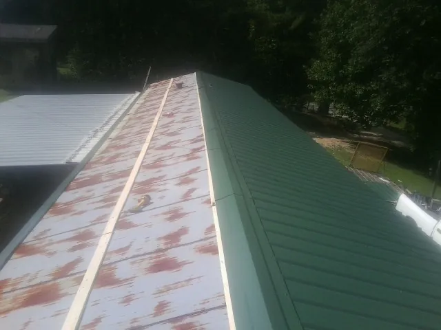 Old rusted panels beside newly installed green metal roofing — Wind Damage Roof Repair by Roofing Brothers in Hedgesville