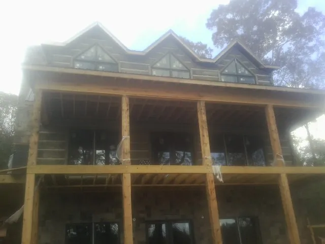 Dormers and porch framing on a large log home under construction — Roof Coating work by our crew in Hedgesville