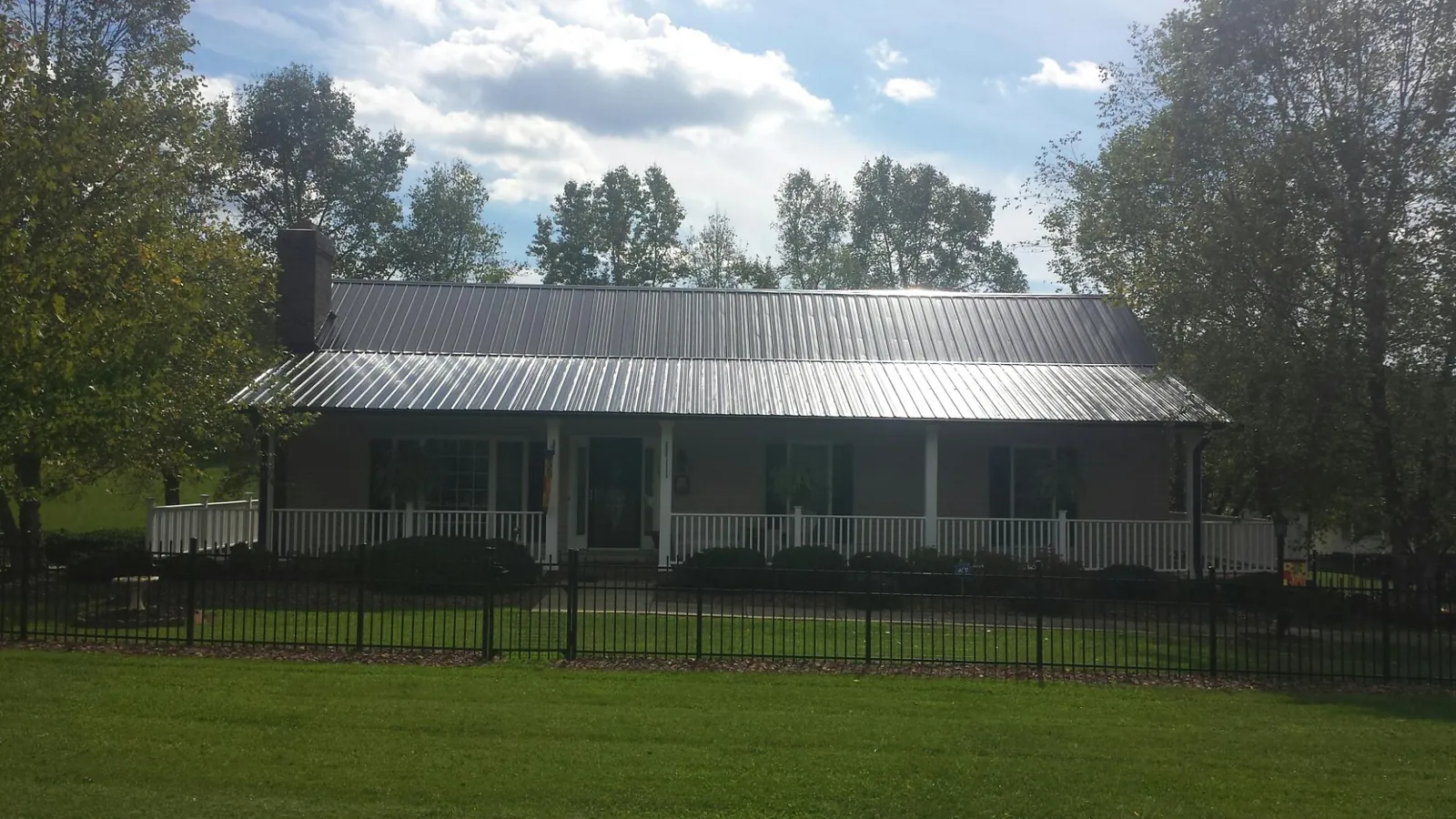 Gray metal roof on a brick ranch with a full width front porch — Gutter Guard Installation work by our crew in Hedgesville
