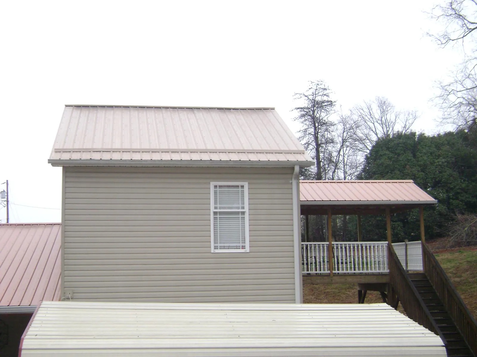 Tan metal roofs on a two story addition and attached porch, from a Roof Replacement job in Hedgesville