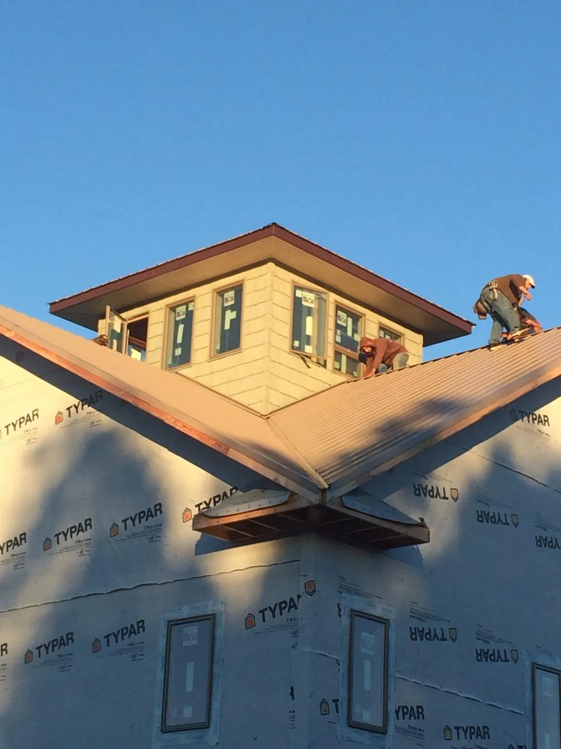 Roofers working around a rooftop cupola on a new metal roof at sunset — Roof Waterproofing in Hedgesville by Roofing Brothers